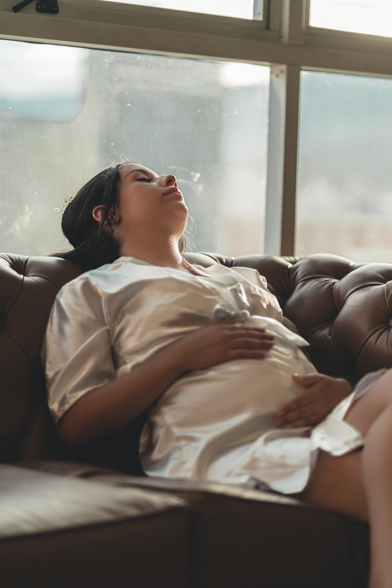 Serene pregnant woman lying on cozy sofa with eyes closed